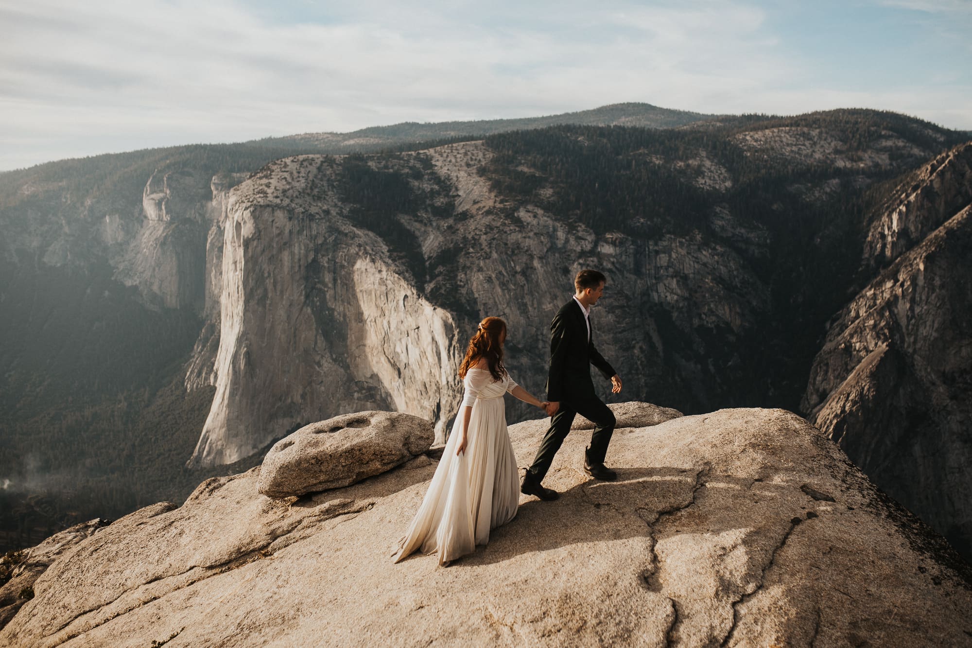 Couple walks along granite cliff in Yosemite during their elopement